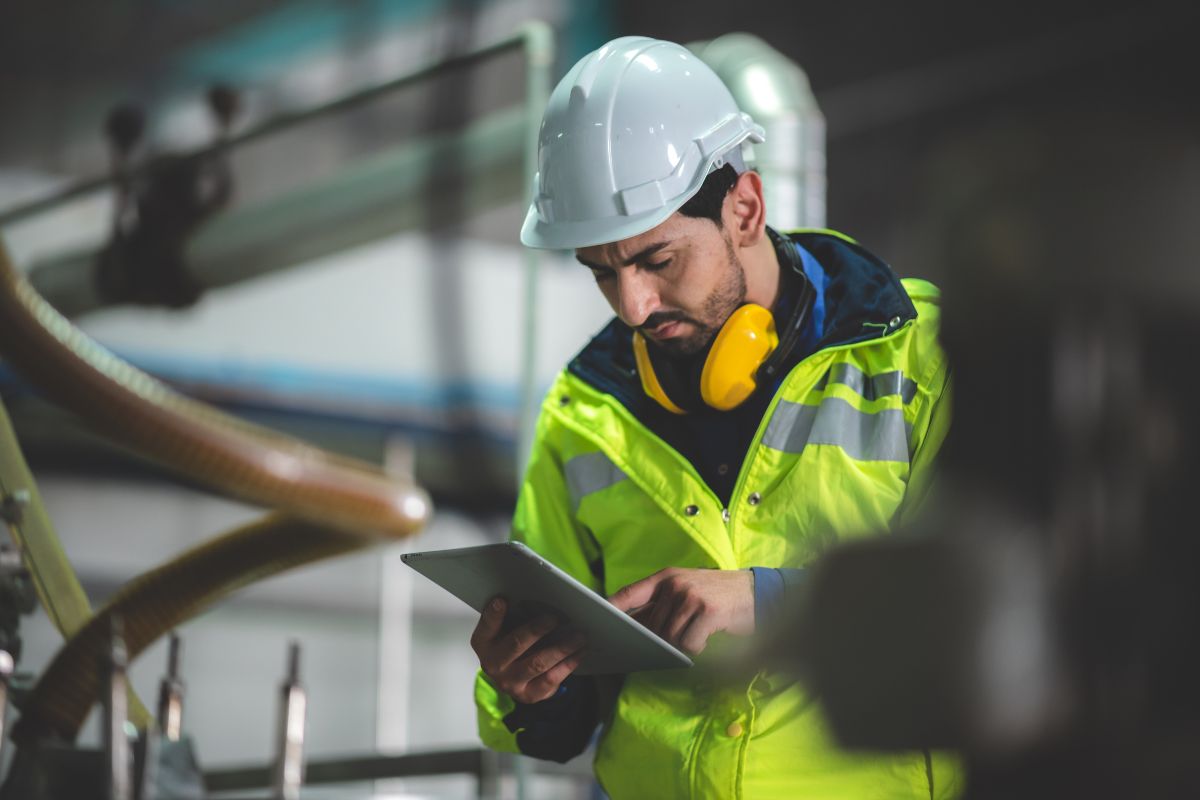 Hydrocycle - Technicien expert en veste réfléchissante utilisant une tablette numérique dans un environnement industriel pour surveiller les systèmes